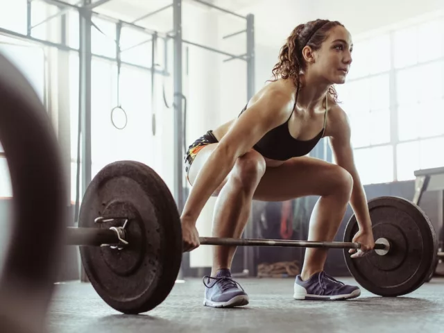 Woman doing deadlifts at the gym to complete her functional fitness routine