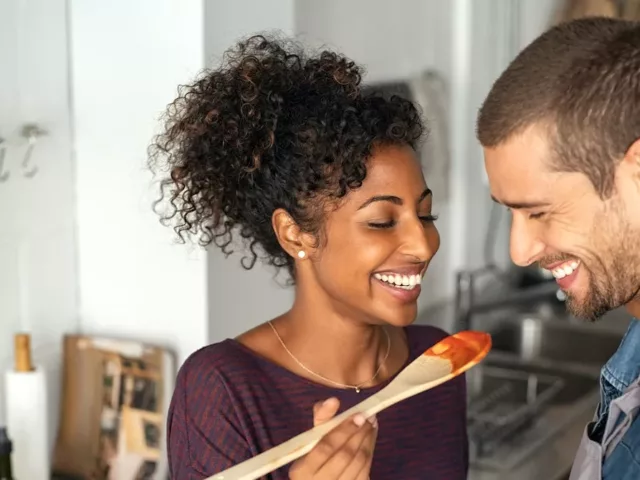 Young couple tasting dinner during prep, enjoying their time together as a component of mindful eating