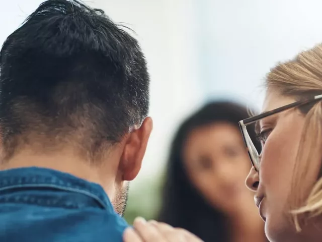 Woman consoling crying husband in a therapy setting, getting his emotions out to reap the benefits of crying