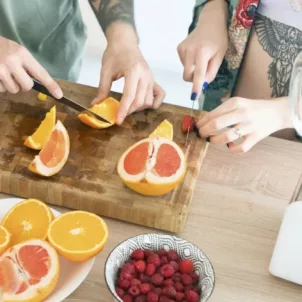 Couple making a morning smoothie at the kitchen island with foods that pack the best vitamins for glowing skin, such as vitamin C