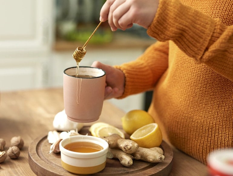 Woman making ginger tea with honey and lemon to relieve cramps