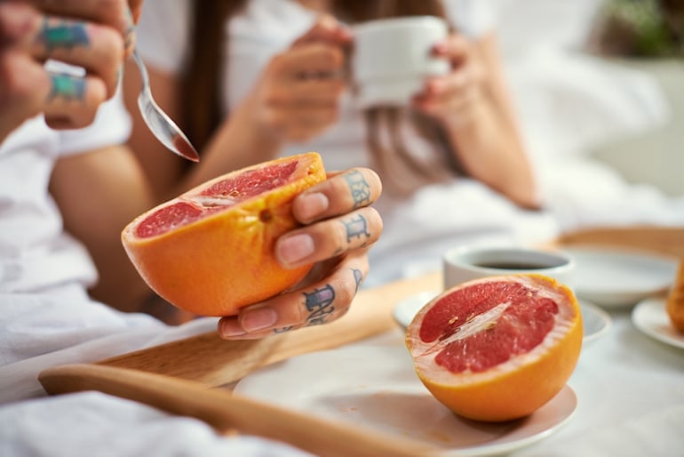 Couple eating grapefruit and coffee in bed