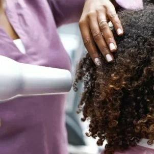 Side profile of a Black woman drying her natural hair at a salon