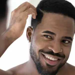 Black man running fingers through his hair, wondering if he should use coconut oil