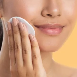 Woman exfoliating her sensitive skin with lactic acid toner on a cotton pad