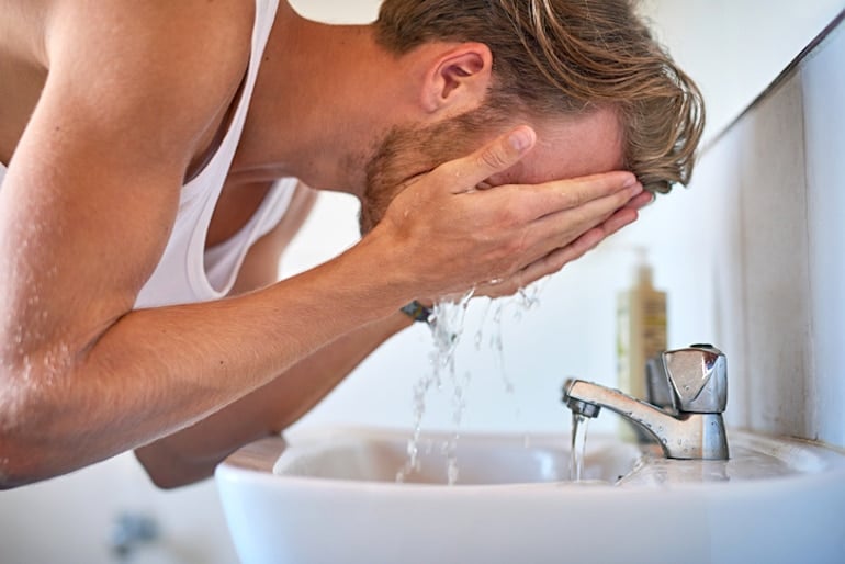 Young man washing his face and beard before exfoliating with lactic acid