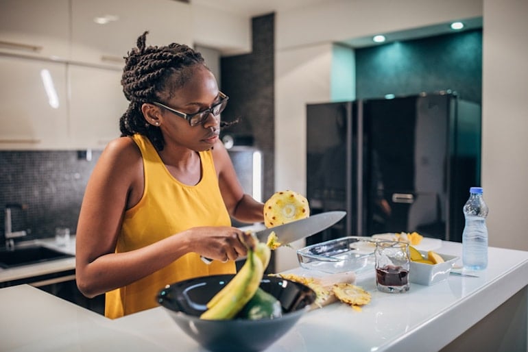 Woman cutting pineapples since they can help reduce cramps