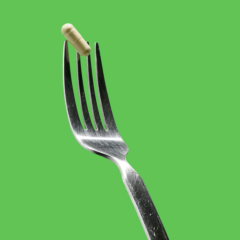 Probiotic capsule on a fork to illustrate the question, should you take probiotics with food?