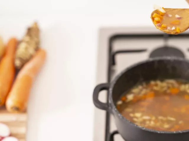 Woman cooking bone broth with vegetables for hyaluronic acid benefits