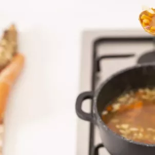 Woman cooking bone broth with vegetables for hyaluronic acid benefits