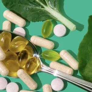 Personalized HUM vitamins and supplements on a spoon next to leaves on a bright green background, to demonstrate how to find the best vitamins for you