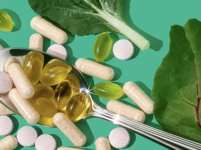 Personalized HUM vitamins and supplements on a spoon next to leaves on a bright green background, to demonstrate how to find the best vitamins for you