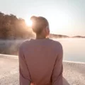 Woman sitting by a lake at sunrise, enjoying the minimal lifestyle, simple joy of living, and psychological benefits of minimalism