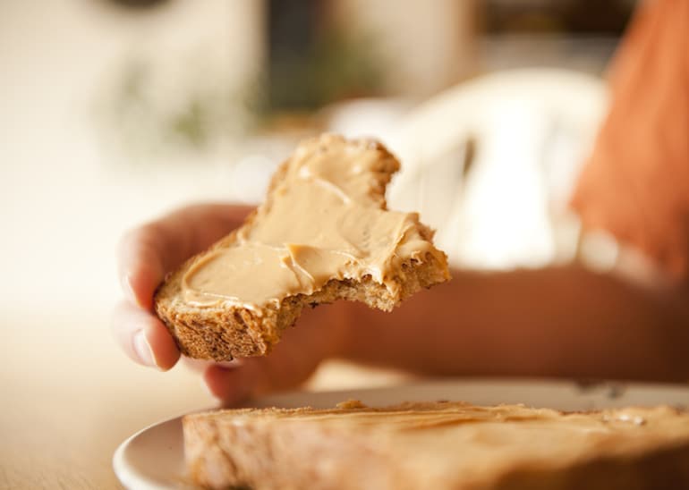 Woman eating whole wheat toast with nut butter for fiber and anal health