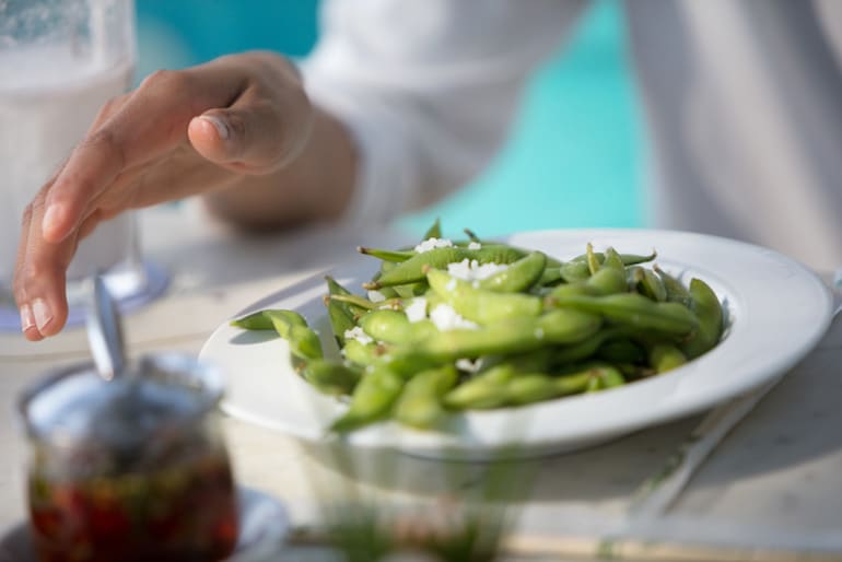 Mature woman eating edamame at a restaurant, a good food for hot flash relief