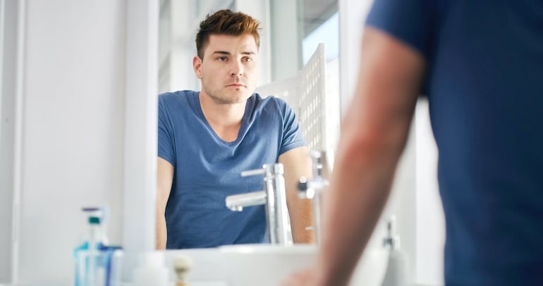 Man evaluating toxic positivity in mirror