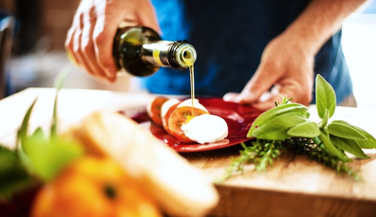 Man pouring extra virgin olive oil for caprese