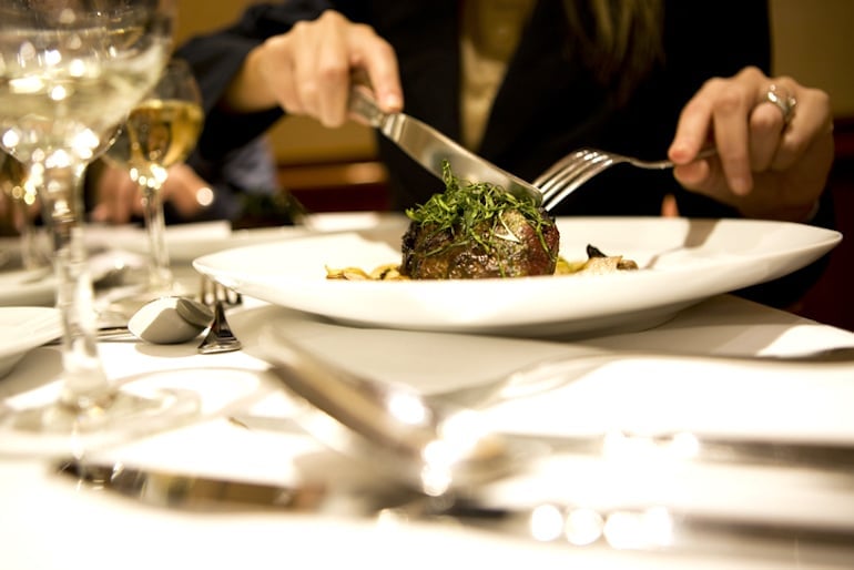 Woman eating steak, high in vitamin B, which could lead to bright yellow pee