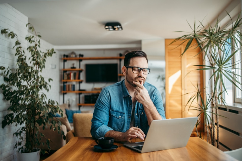 Puzzled man searching for answers on computer, illustrating poor long-term memory formation from excessive internet use