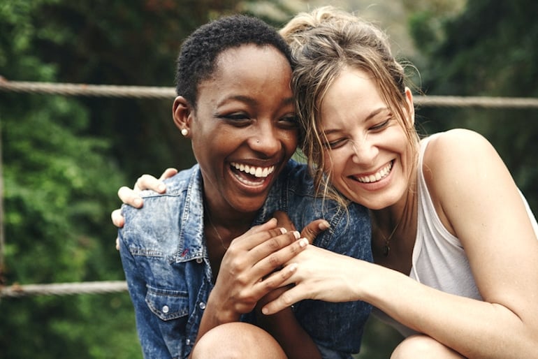 Two girl friends laughing, illustrating that psychological benefits of minimalism are happiness and less loneliness