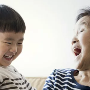 Grandma and grandson laughing on the couch, with the grandma's happiness getting better with age