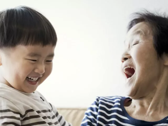 Grandma and grandson laughing on the couch, with the grandma's happiness getting better with age