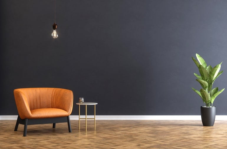 Minimalist home with blank black wall and orange leather armchair and plant