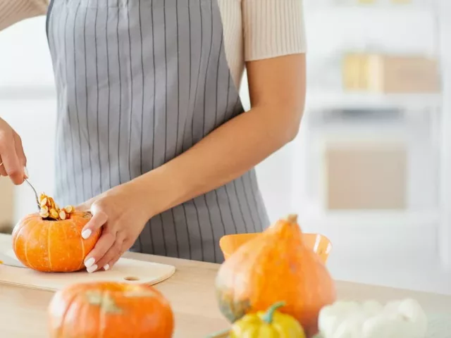 Woman scooping out pumpkin to cook to get their health benefits