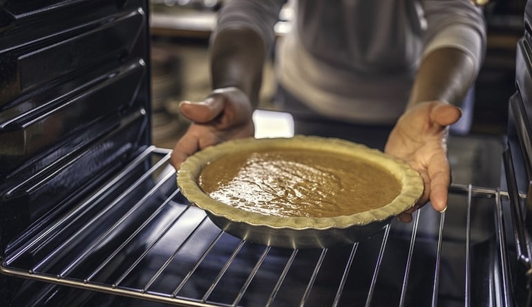 Man baking pumpkin pie in the fall to reap the benefits of eating pumpkin