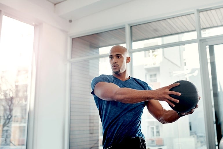 Man strength training with a weighted ball to get stronger, lose fat, and gain confidence