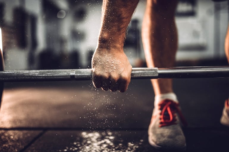 Man lifting barbell in gym to show the benefits of strength training