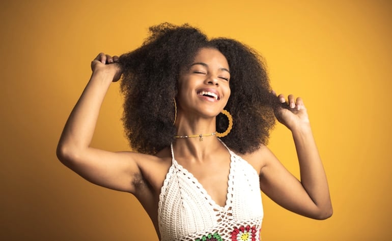 Happy woman showing her female body hair under her arms; body hair positivity concept