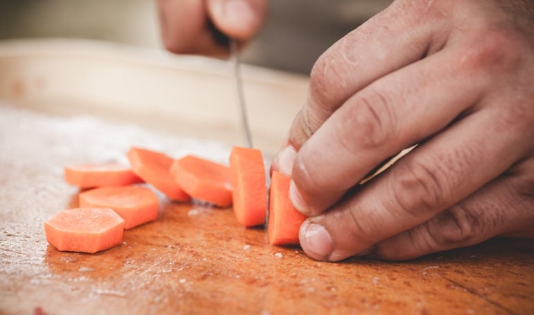 Man slicing carrots, one of the best foods to eat for sperm count and health