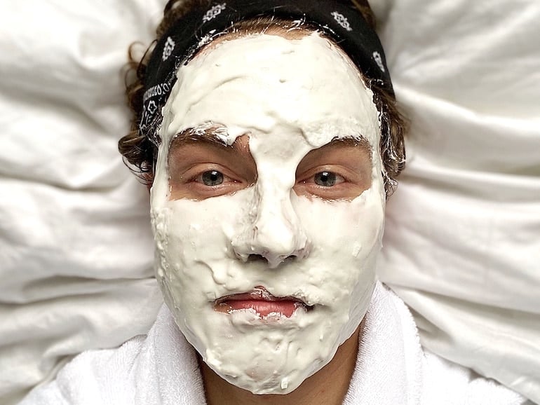 Garrett Munce, grooming editor and author of Self-Care for Men, with a face mask and bandana during his men's skincare routine