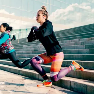 Two women doing lunges on stairs to reap the health benefits of strength training