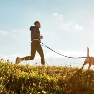 Man running with dog in nature to show how exercise reduces stress