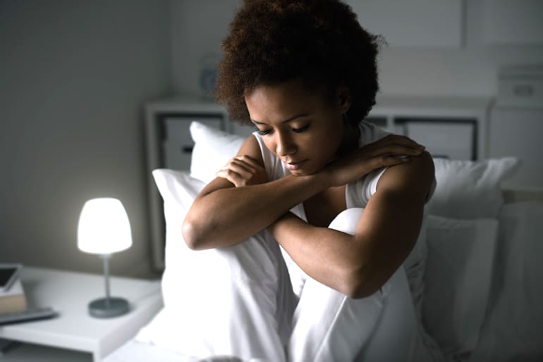 Woman stressed in bed to show how stress and sleep quality are related