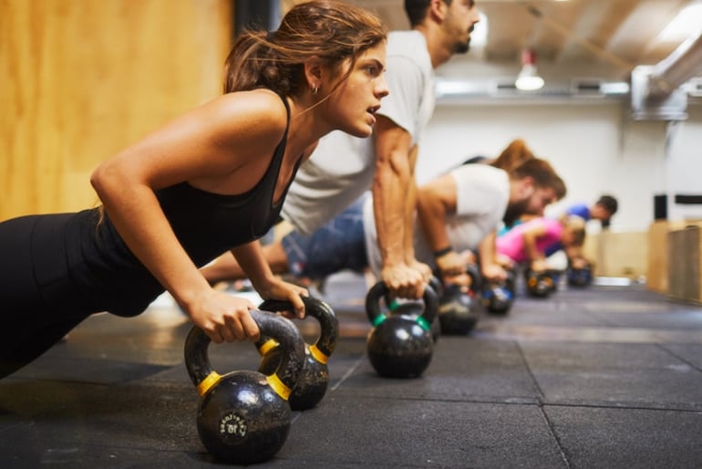 Group strength training class with kettlebells, doing pushups