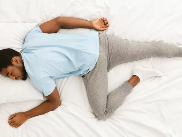 Overhead shot of man sleeping on his stomach to intro article on what your sleeping position says about you