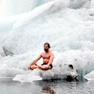 The Iceman Wim Hof sitting on a block of ice, practicing the Wim Hof Method of cold therapy and breathwork