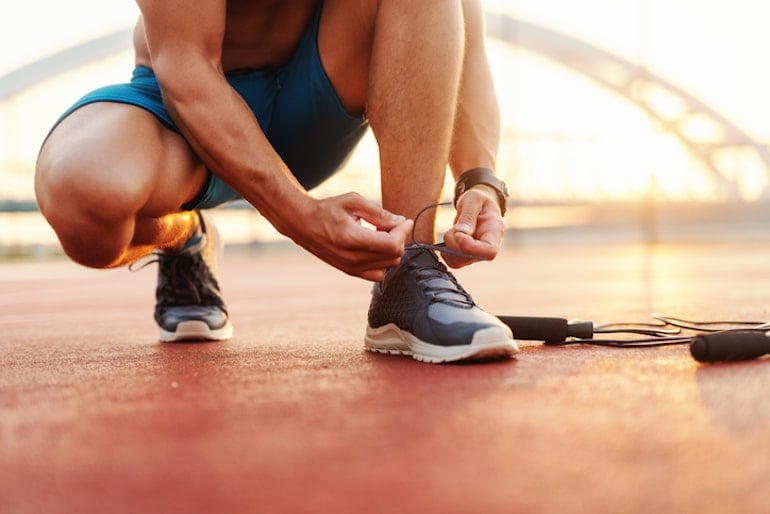 Man tying sneakers outdoors before a morning exercise