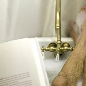 Man reading in bathtub to illustrate self-care for men ideas