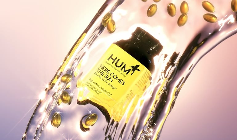 HUM Here Comes the Sun vegan vitamin D supplement for immunity in stream of water on pink/purple background