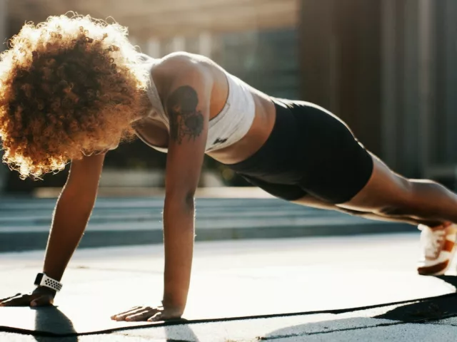 Woman in plank position exercising outdoors to boost her immune system