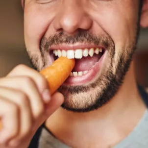 Man chewing into a carrot to illustrate how many times you're supposed to chew your food