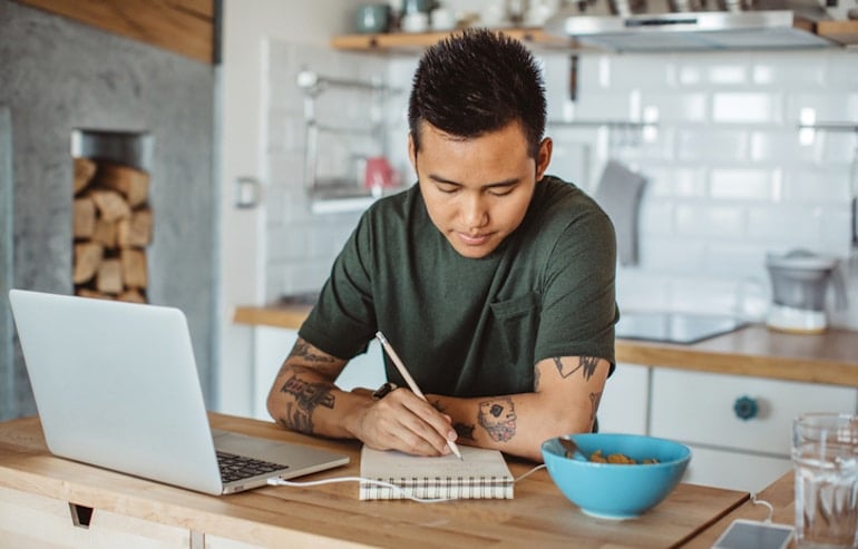 Man in kitchen writing down good questions to ask a dietitian to prepare for his consultation