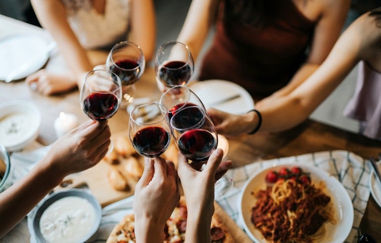 Friends doing cheers with wine to illustrate how to navigate social dining on a nutritionist-advised meal plan