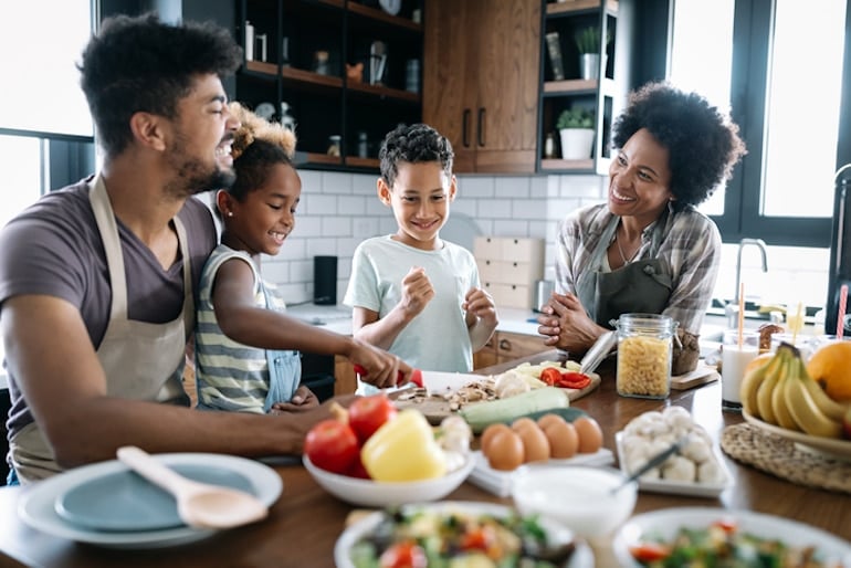 Family of four preparing a meal together with vegetables