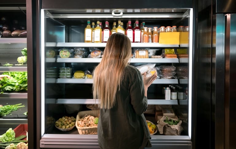 Woman reading food labels at speciality health store to see if a certain diet is good for her