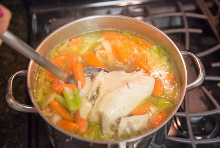 Woman making homemade chicken soup, one of the best foods to eat when you're sick